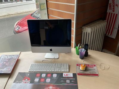 a desk with a computer, keyboard, mouse, and magazines on it