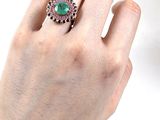 la main d'une personne tenant une bague sertie d'une pierre verte