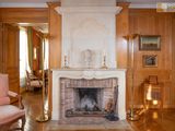 a fireplace in the middle of a living room with wood paneled walls