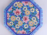 une image représentant une assiette décorative ornée de fleurs sur fond bleu