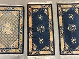 three oriental rugs are lined up on a table