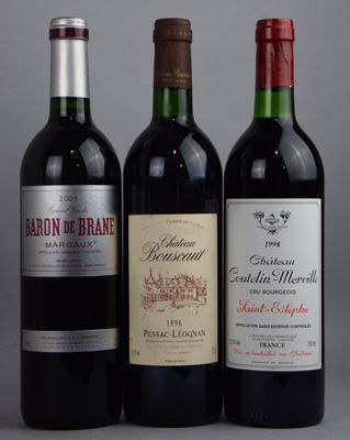 trois bouteilles de vin rouge sont alignées sur une surface grise