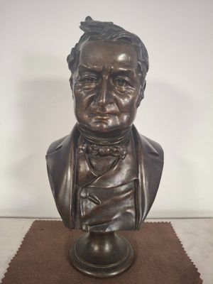 bronze bust of a man with a bow tie on a table