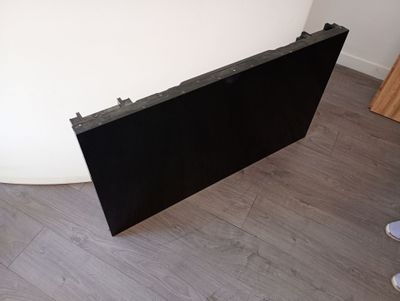 un tableau noir posé par terre, près d'un mur blanc