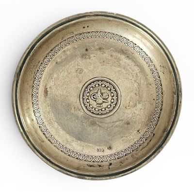 une assiette ancienne en argent sur fond blanc, ornée d'un motif décoratif