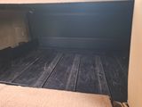 a truck bed that has been painted black and has a wooden floor