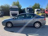 a silver car parked in a parking lot with trucks in the background