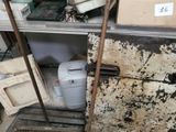 a small refrigerator in the corner of a room with a lot of stuff on the floor
