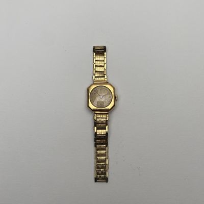 a gold watch on a white surface with a white background