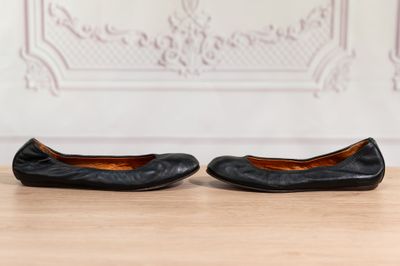 une paire de ballerines en cuir noir posées sur un parquet