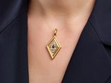 a close up of a woman wearing a gold necklace with a red and white diamond