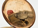 a close up of a pocket watch on a white surface