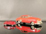 une petite voiture rouge et une autre petite voiture rouge posées sur une surface noire