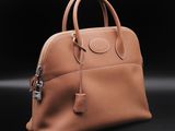a brown leather handbag on a black background