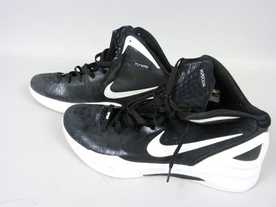 une paire de chaussures de basket Nike noires et blanches posées sur une surface blanche