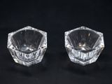 pair of clear glass candle holders on a black background
