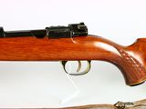 someone is holding a rifle with a wooden handle on a white surface