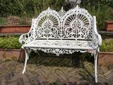 un banc blanc qui se trouve au milieu d'un jardin
