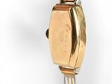 a gold watch on a fork on a white surface