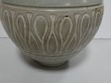a white vase sitting on a table with a white wall in the background