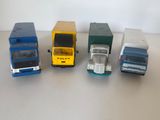 Plusieurs camions miniatures sont alignés sur une surface blanche