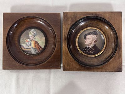 pair of framed portraits of a man and a woman in a wood frame