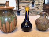 three vases sitting on a table with a stone wall in the background
