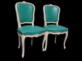 pair of turquoise and white chairs against a black background