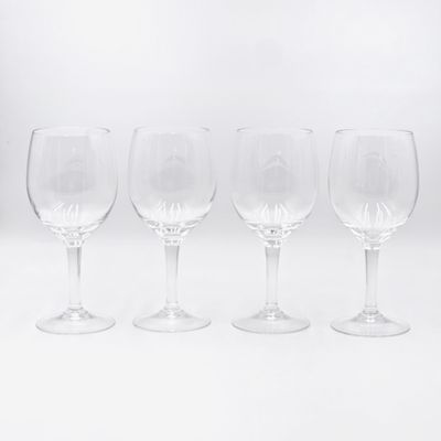quatre verres à vin vides alignés en rang sur une surface blanche