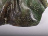 a bronze statue of a woman sitting on a rock