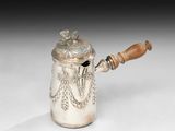 une cafetière en argent avec une poignée en bois sur une surface blanche
