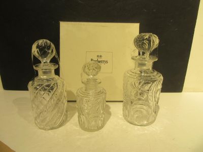 trois flacons de parfum en verre posés sur une table, à côté d'une boîte