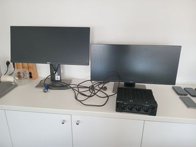 deux écrans et un ordinateur portable posés sur un bureau blanc