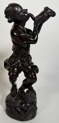 a statue of a boy playing a trumpet on a rock