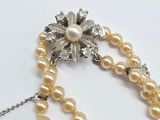 a necklace with pearls and a broocher on it