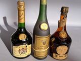 trois bouteilles d'alcool sont alignées sur une surface blanche