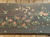 a black table with flowers and birds painted on it