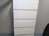 a picture of a white chest of drawers in the corner of a room