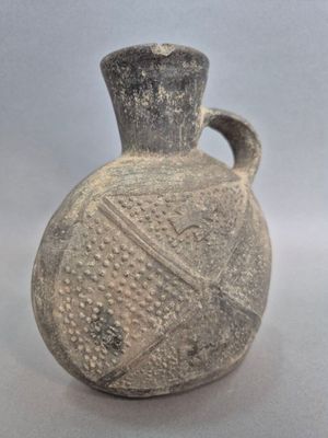 un petit vase muni d'une anse, posé sur une table