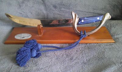 un couteau posé sur un support en bois orné d'un pompon bleu