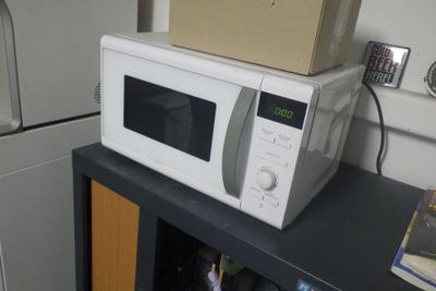 un micro-ondes posé sur un meuble, avec une boîte dessus