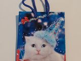 un chat blanc coiffé d'un chapeau de fête, posé sur un sac-cadeau