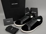 des baskets noires et blanches, avec une boîte noire et un sac noir