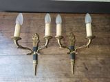 three brass wall sconces mounted on a wooden wall