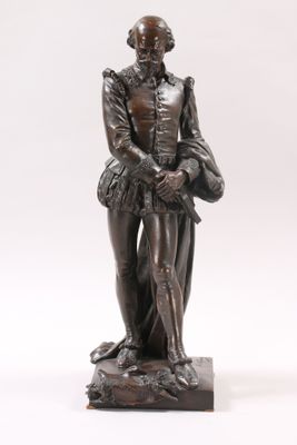 an antique bronze statue of a man with a hat and a cane