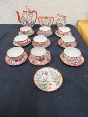 many cups and saucers on a table with a black table cloth