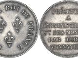 a close up of a silver coin with a fleur on it