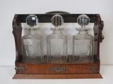 three glass bottles in a wooden holder on a table