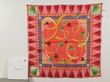 a red and yellow scarf hanging on a wall next to a white box