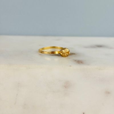 La bague en or est posée sur une table en marbre.